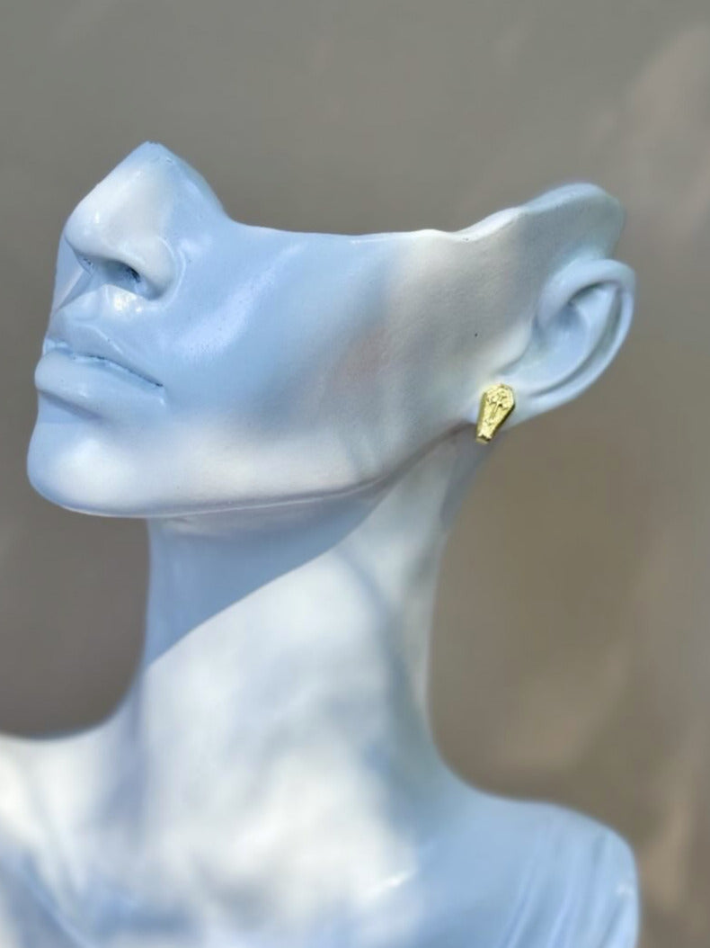 Blue mannequin bust with a gold earring against a neutral background
