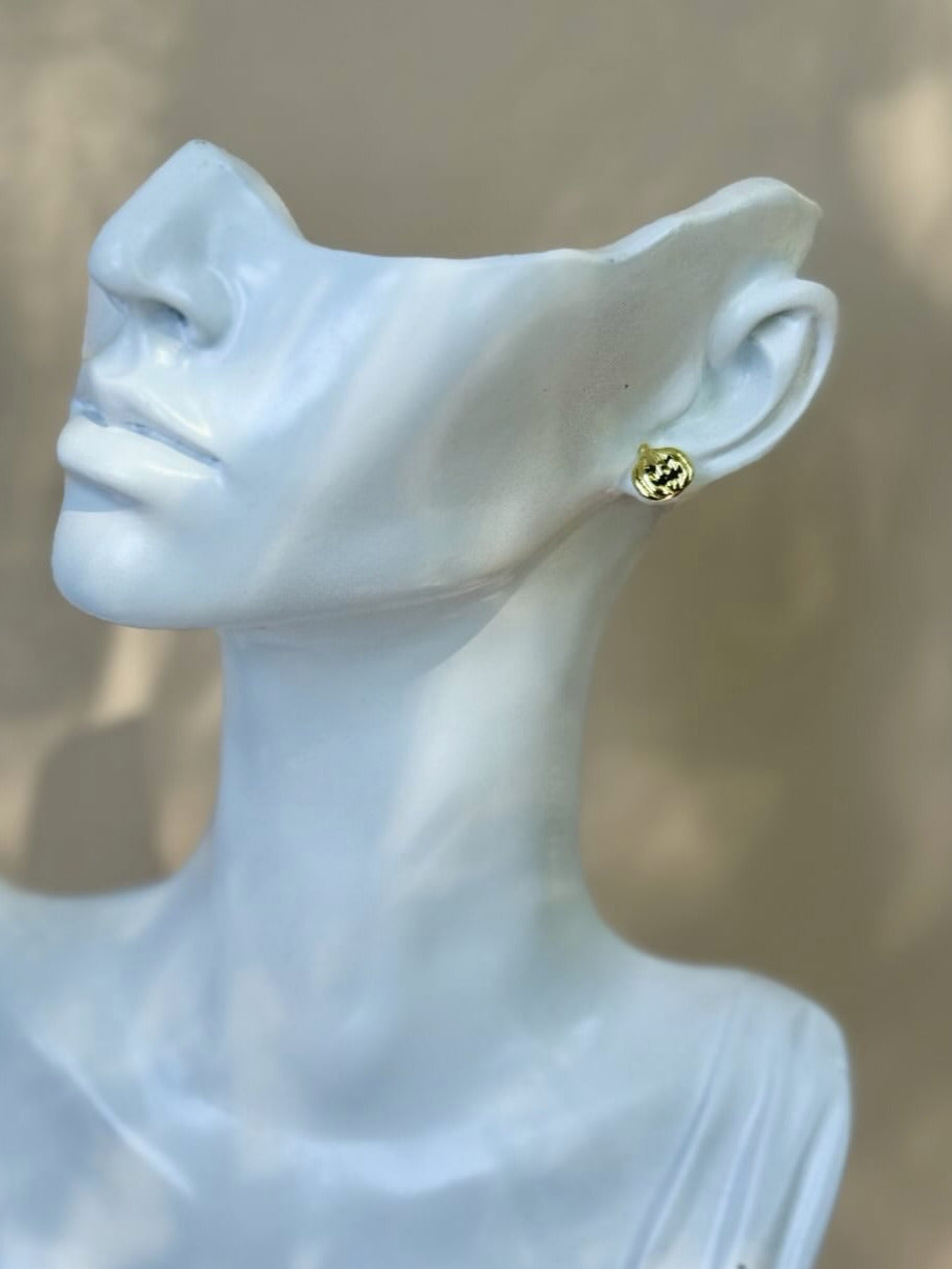 Gold earring on a mannequin bust against a neutral background