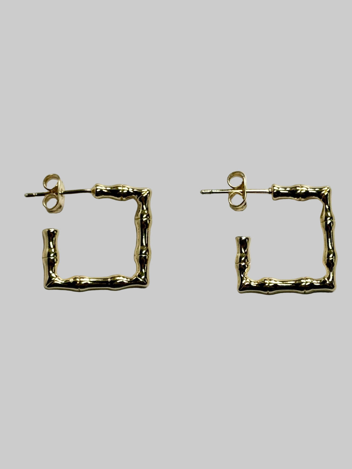 Gold square hoop earrings on a light gray background