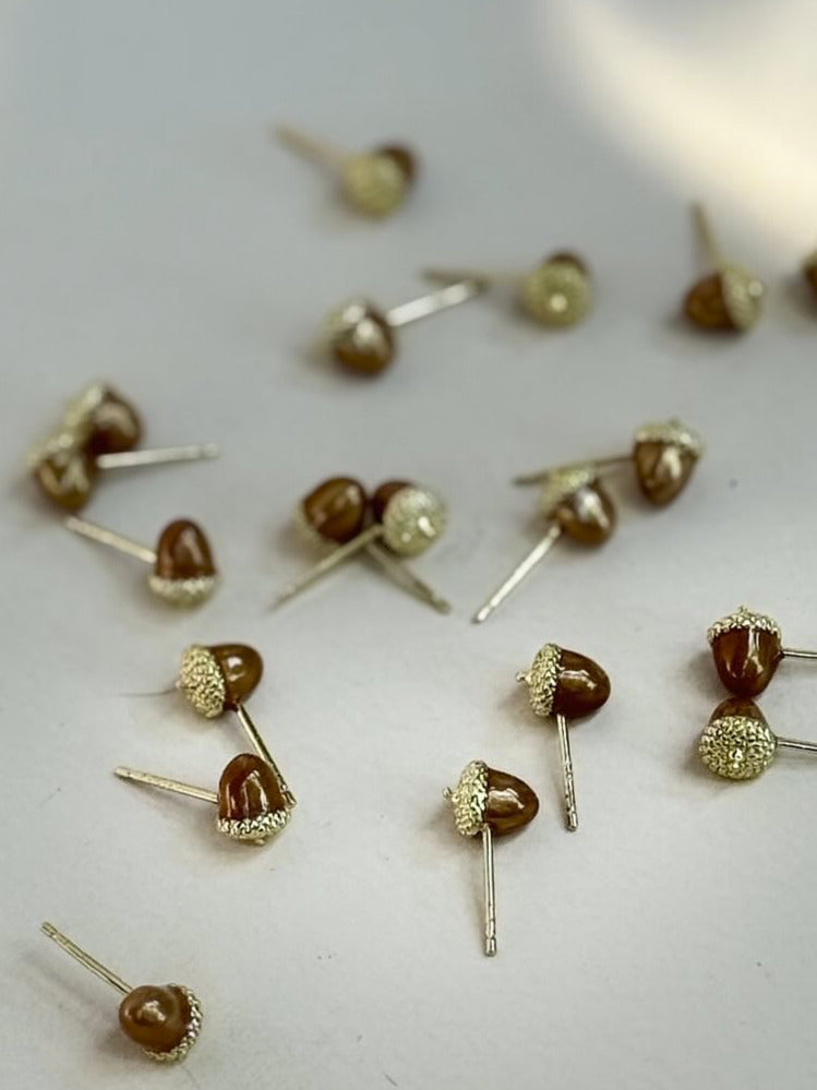 Small gold and brown earrings scattered on a light surface