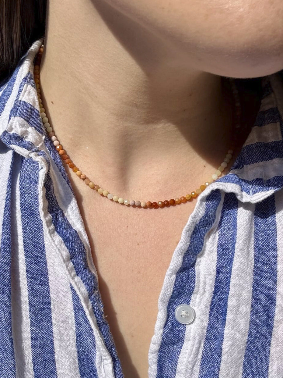 Person wearing a blue and white striped shirt with a necklace