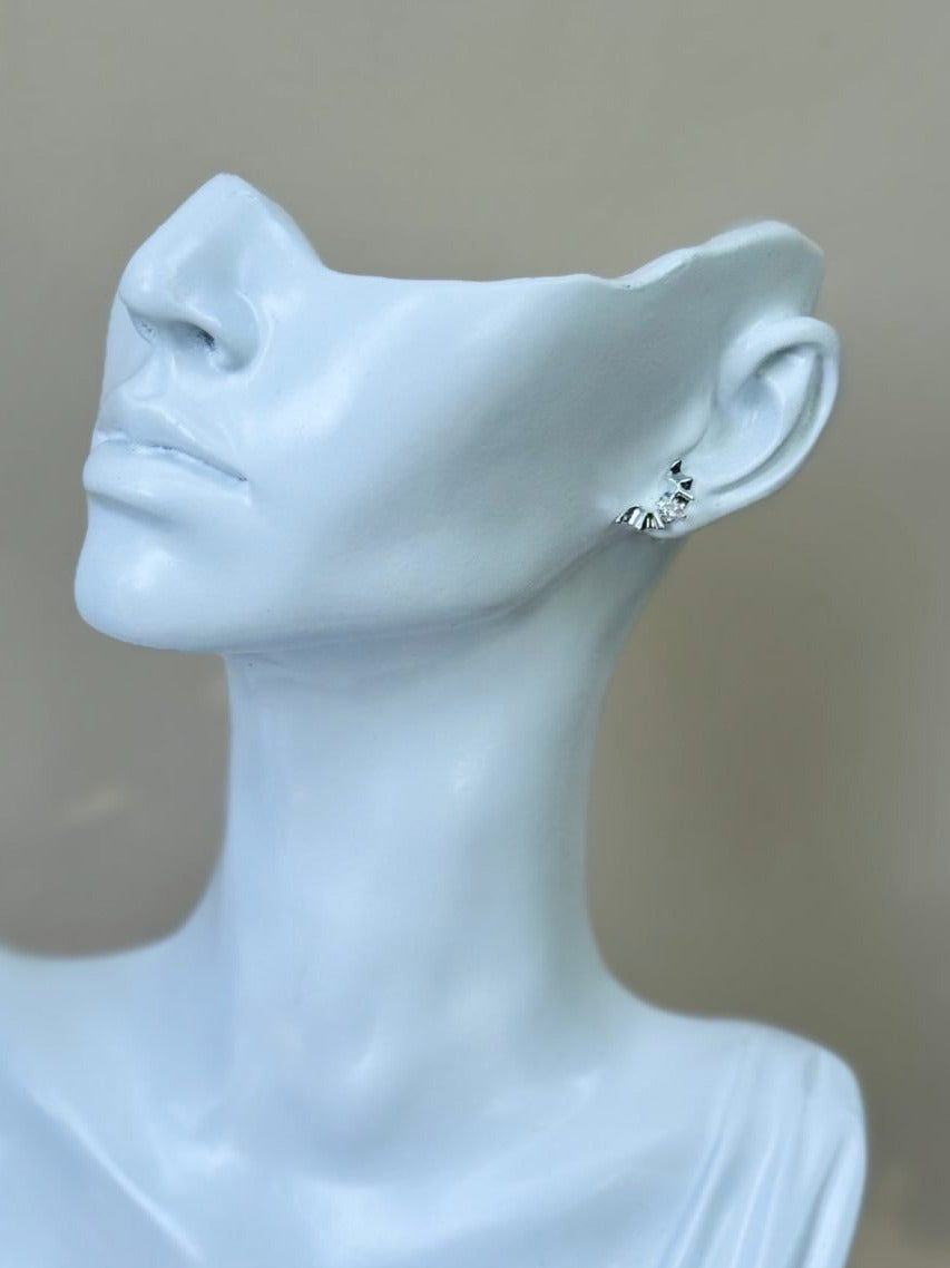 Mannequin bust wearing a silver earring against a neutral background