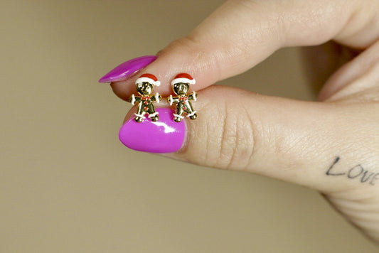 Person wearing small earrings with Santa hats on a blurred background